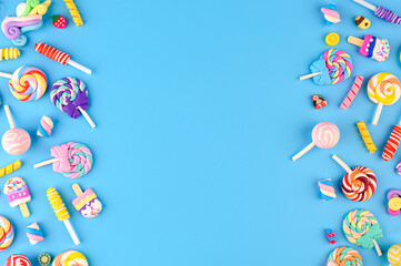 Frame made of decorative sweets, lollipops and ice cream. Top view on blue background