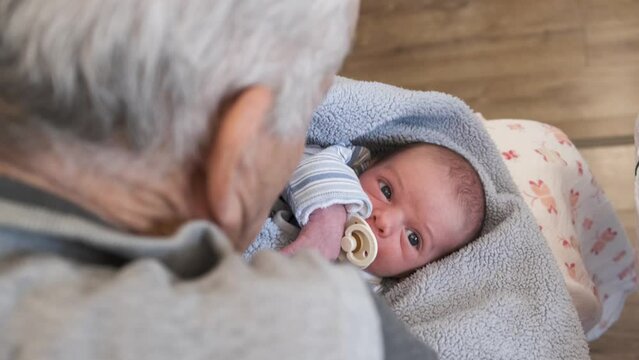 grandpa with baby. Baby on grandfather's lap. newborn infant looking up at the camera. old man holding baby with pacifier. infant looking up with huge beautiful eyes. soft little baby. life concept. 