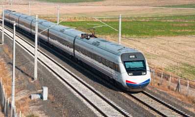 Fototapeta na wymiar Blue high speed train runs on rail tracks - The train is going too fast 