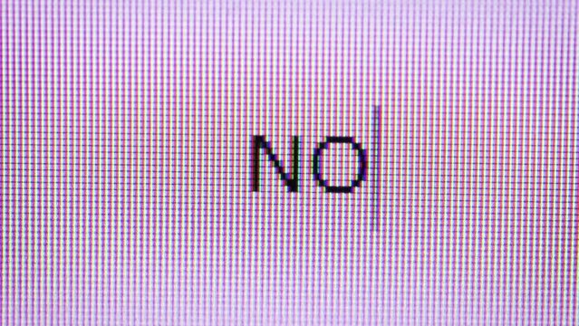 モニターにタイピングされるNOの文字。文字のクローズアップ。否定。
