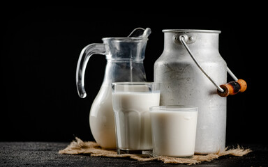 Rustic milk in a can and a glass on the table. 