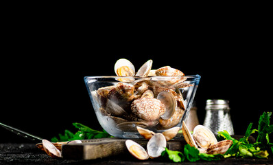 Fresh vongole in the bowl on a cutting board with parsley. 