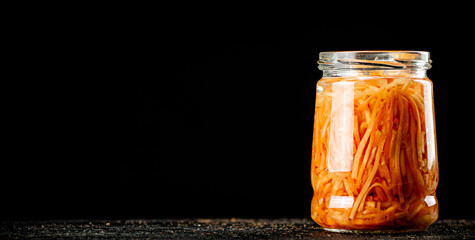 A glass jar with canned carrots. 