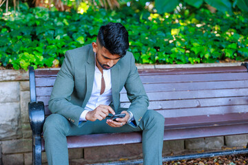 ベンチに座り携帯電話を眺めるビジネスマン男性