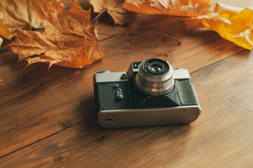 Autumn composition. Retro camera, autumn leaves, checkers on a wooden background. The view from top. - Powered by Adobe