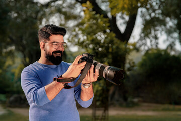 Young indian man using camera equipment at park