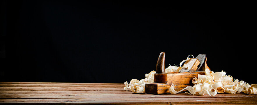 Hand planer on wood. On a black background.