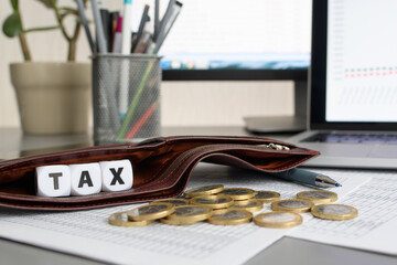 The inscription Tax in an empty wallet next to scattered coins. The concept of paying high taxes on...