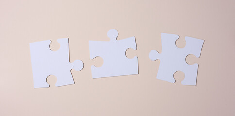 Empty white big puzzles on a beige background. Concept in business