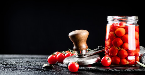 Pickled tomatoes in a glass jar on the table. 