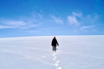 person walking on snow a track behind