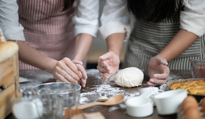 Obraz na płótnie Canvas Women chef knead dough in kitchen for fresh homemade cooking, bakery or bread. Female hands thresh flour on table preparing for delicious pizza baking. Happy Asian family making dinner meal together.