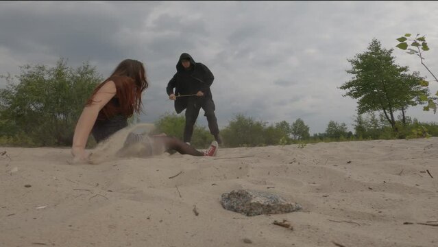 Cinematic shot  maniac in black clothes with rope in hands trying to kill his victim  in a wasteland outside the city, but girl  finding stone and hitting him on the head. True crime concept 