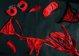 Leather red whip and handcuffs ,underpants, feather, mask on a black  background. Sex toy. Flat lay. Top view. VALENTINE'S DAY