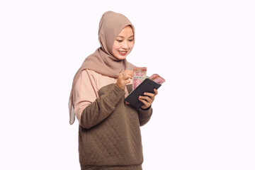 Portrait of happy Asian Muslim woman holding rupiah money and wallet isolated on white background