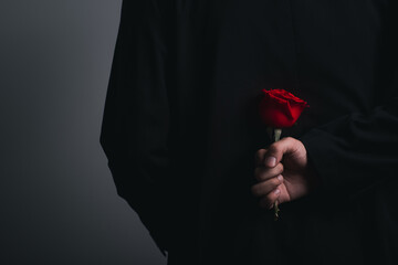 hands crossed behind man hand wearing suite with red rose flower on background. holidays card with copy space valentine day celebration concept.	