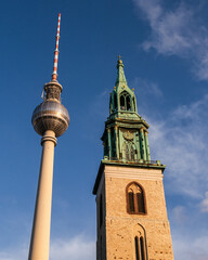 Église Sainte-Marie et Fernsehturm  de Berlin un soir ensoleillé avec peu de nuages
