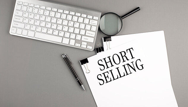 SHORT SELLING text on paper with keyboard, magnifier and pen. Business concept