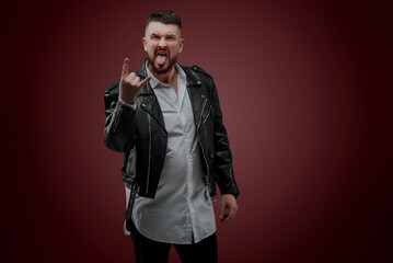 The man is dressed in a Ukrainian shirt; a man in a leather jacket poses on a red background; shows different facial expressions and gestures; poses in sunglasses in the studio; charismatic portrait o