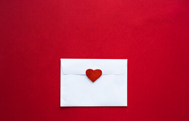 Romantic love letter in white envelope with Valentines heart on red background. Flat lay, top view, copy space. Happy Valentine's Day concept