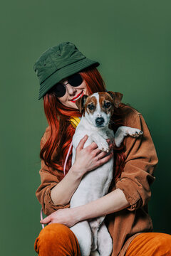 Stylish Redhead Woman With Headphones And Dog On Green Background