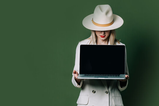 Stylish blond hair woman with laptop on green background