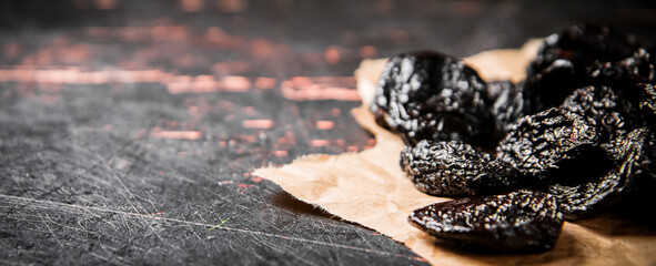 Prunes on paper on the table. 