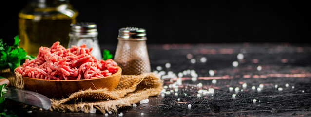 Minced meat in a plate on burlap with spices. 