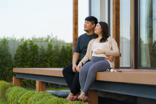 Asian pregnant woman with her husband talking together in terrace at home for relax and breath of fresh air.