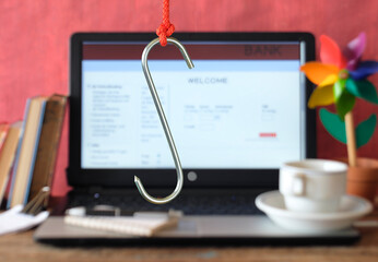 data phishing, big hook on laptop computer showing fictional online banking phishing website, blurred in the background