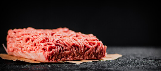 Raw minced meat on paper on the table. 