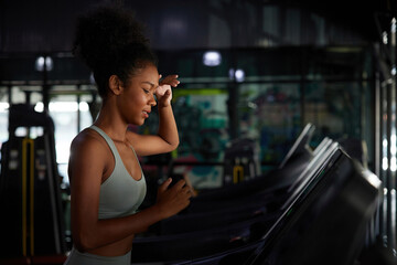 Fototapeta na wymiar young sports woman working out, running and feeling tired on treadmill in gym