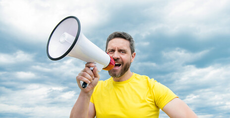 man in yellow shirt shout in loudspeaker on sky background. promotion