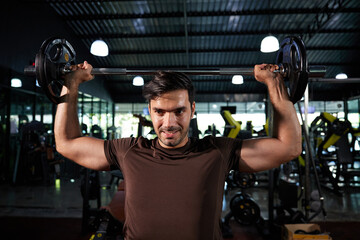 young athletic man exercising with barbell in the gym