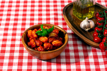 gnocchi with tomatoes and basil in a wooden bowl on a red checkered tablecloth