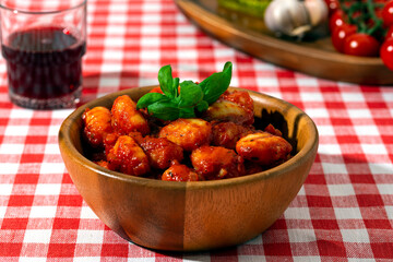 gnocchi with tomatoes and basil in a wooden bowl on a red checkered tablecloth