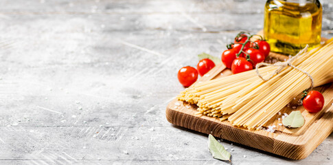 Spaghetti dry on a wooden cutting board with tomatoes. 