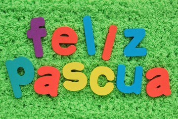 Feliz Pascua, Happy Easter on spanish colored lettering on green grass background. Holiday spring compostion concept. Creative idea for greeting card, poster, banner, invitation. Top view, flat lay