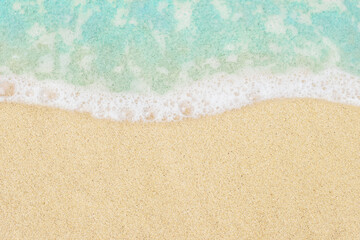 Fototapeta na wymiar Soft ocean wave on beach background in top view. Blue sea water and textured sand close-up with copy space for text and design