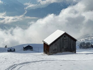 Indigenous alpine huts and wooden cattle stables in the Swiss Alps covered with fresh first snow over the Lake Walen or Lake Walenstadt (Walensee), Amden - Canton of St. Gallen, Switzerland / Schweiz