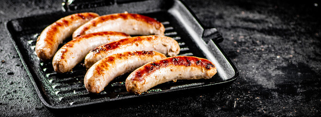 Grilled sausages in a frying pan. 