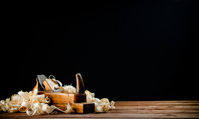 Hand planer on wood. On a black background.