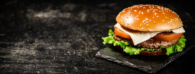 A burger on a stone board on a table. 