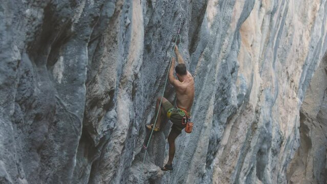 Extreme sport, a strong man climbs a rock, a rock climber climbs a difficult route.