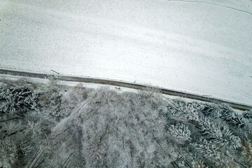Top view of snow covered woodland with rural road at City of Zürich on a late autumn morning....