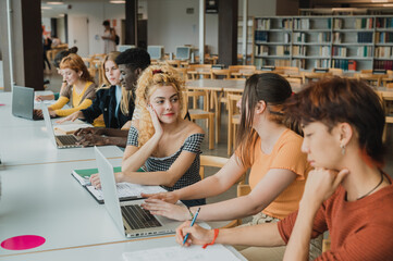Focused multiracial classmates using netbook in library while doing research
