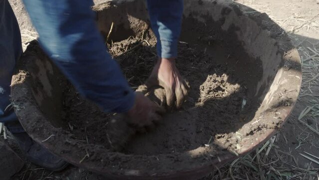 person mixing straw and earth for the technical construction of bioconstruction