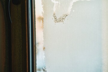 Frozen condensation on the interior window glass. Iced steam and dew on the glass during winter.