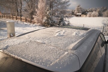 Modern car roof covered with snow on a sunny winter day. The panoramic sunroof in the winter.