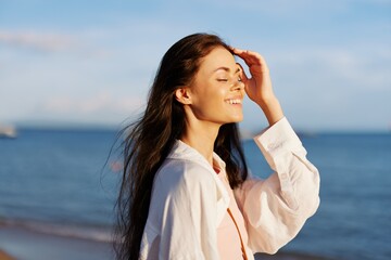 Woman portrait smile with teeth freedom on vacation walking on the beach by the ocean in Bali sunset, happy travel and vacation, sunset light, flying hair, skin and hair care concept in the sun